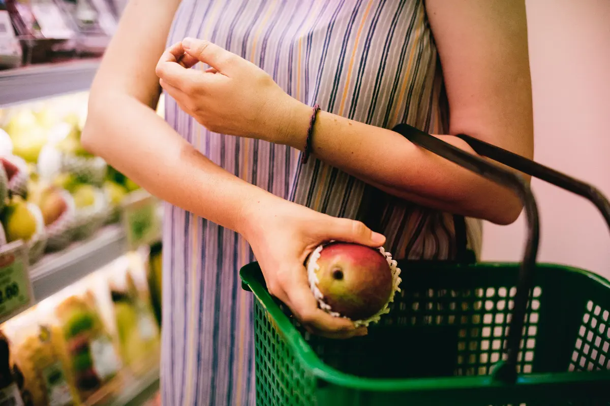 Donna che mette un mango nel cestino